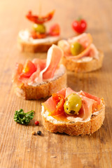 bread toast with cheese, prosciutto ham and olive