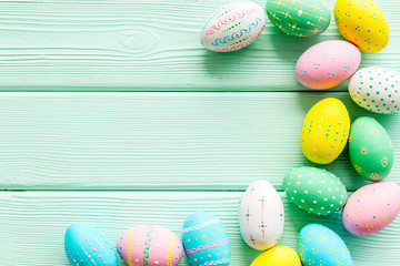 Colorful Easter eggs frame on green wooden background top-down copy space