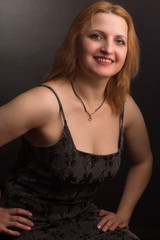 portrait of large blonde model in a black dress on a dark background in the Studio