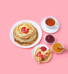 Pancake week, Maslenitsa concept. Pancakes, Cup of tea and sweets - honey, jam on pink background. Breakfast with Homemade Pancakes.