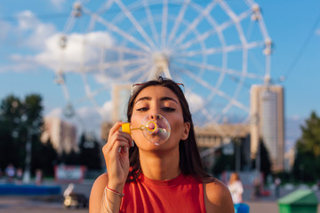 Fototapeta premium Beautiful young woman blowing soap bubbles outdoors