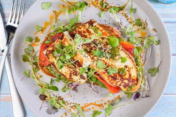 A serving of Baked Ricotta, Capsicum and Pesto placed on a slice of toasted bread, surrounded by salad.