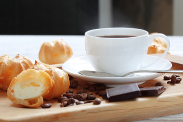 Profiterole with cream and a cup of coffee with chocolate