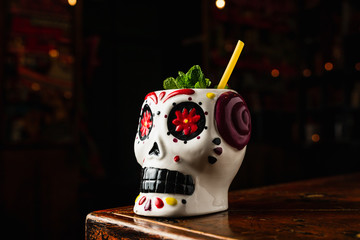 A refreshing cocktail in a tiki mexican style scull glass with an eco straw made from a spaghetti