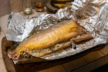 Homemade grilled dorado fish with vegetables wrapped in aluminum foil on rustic table. Top view.