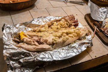 Homemade grilled dorado fish with vegetables wrapped in aluminum foil on rustic table. Top view.