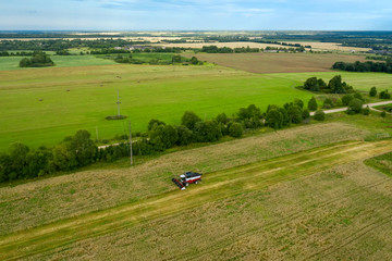 Aerial view of an agricultural field and harvester harvesting in autumn day