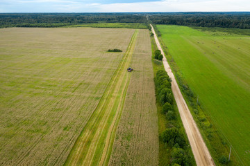 Aerial view of an agricultural field and harvester harvesting in autumn day