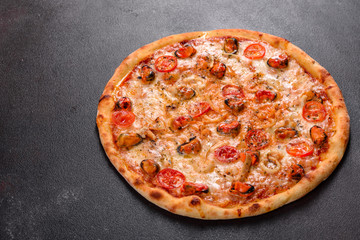 Tasty sliced pizza with seafood and tomato on a concrete background