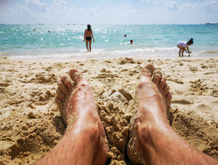 Feet of a man in the sand on the beach