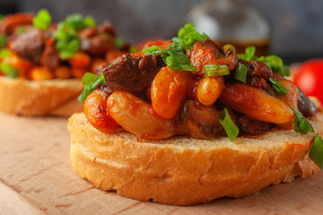 Bruschetta with beans and mushrooms on a wooden board