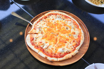 Hot pizza served on wood tray against on black table