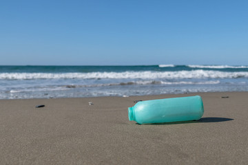 Plastic soap container on wild polluted sea shore ecosystem, industrial trash