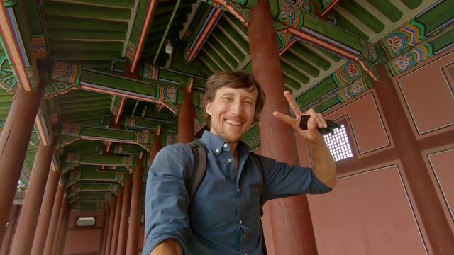 Selfie video. Young man tourist visits an ancient palace in Seoul, South Korea. Travel to Korea concept. Slowmotion shot