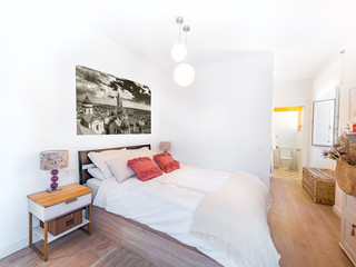 Clean bright bedroom with king size bed, duvet,nightstands, lamps, photography. Minimalist white stylish interior