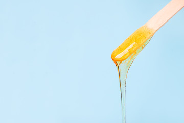 depilation and beauty concept - sugar paste or wax honey for hair removing with wooden waxing spatula sticks on blue background, copy space, beauty industry, concept of smooth skin remove - 321407176