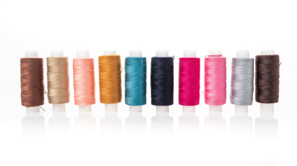 Tailor needles and threads over white.