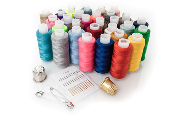 Tailor needles and threads over white.
