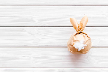 Easter gift in shape of bunny with tail on white wooden background top-down copy space