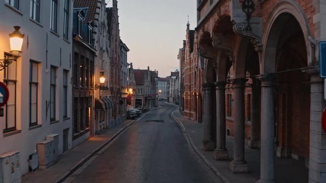 Belgium, Bruges: movement camera along narrow street with warm lights in lanterns on houses in the old center of city