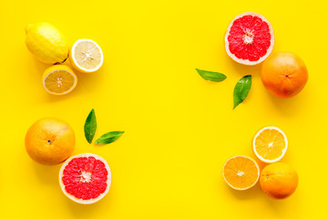 Citrus pattern. Cut lemon and grapefruits and leaves on yellow background top-down copy space