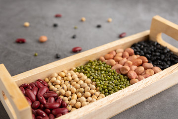 Grains or beans, red bean, black bean, green bean, soybean, peanut in the wooden tray placed on the black cement floor. High angle view.