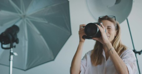 Young professional female photographer taking photos in a photo studio, creative industry jobs concept