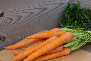 Carrots with a brown paper bag on a wooden background.  Environmentally friendly recycling packaging concept