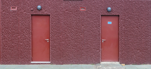 Red wall of a mass production standard low cost residential building with armed doors