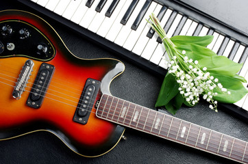 Fototapeta na wymiar Keyboard, electric guitar and a bouquet of lilies of the valley