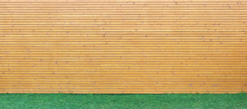 Wellow Wooden Wall From Horizontal Planks And Green Yard  Lawn  Background