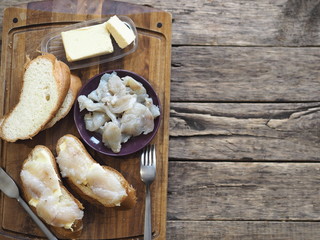 Breakfast, lunch, snack. Sandwiches with butter and freshly salted fish pike on a cutting kitchen board. XE fish salad. Wooden background.