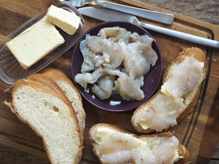 Breakfast, lunch, snack. Sandwiches with butter and freshly salted fish pike on a cutting kitchen board. XE fish salad. Wooden background.