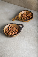 Almonds in a wooden plate on a warm stone concrete board or background. Copyspace.
