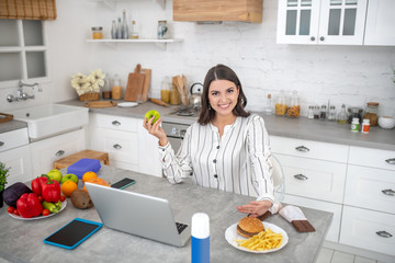 Dark-haired woman in a striped blouse having lunch at home