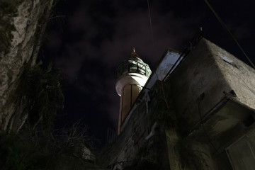 The minaret of the White Mosque rises above the houses against the night sky in the old part of...