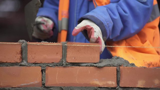 Builder puts a brick building wall