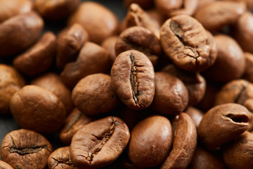 Brown roasted coffee beans on dark background. Espresso dark, aroma, black caffeine drink. Closeup isolated energy mocha, cappuccino ingredient.