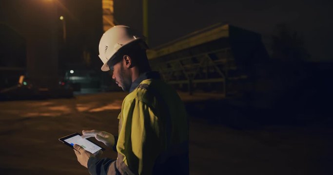 Portrait of stone quarry worker using digital tablet working night shift