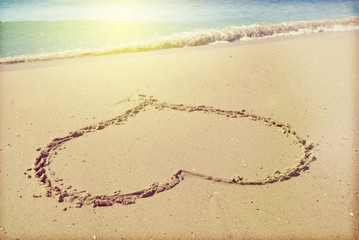 Drawing heart in the sand on the seashore