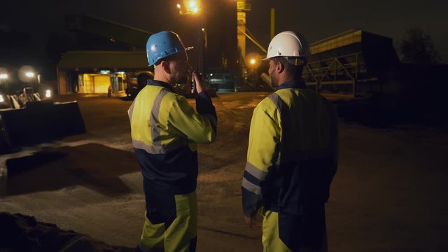 Construction foreman talking on walkie-talkie on construction site working with engineer at night