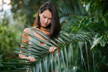 slim young beautiful brunette lady in tropical rainforest , posing and looking down. attractive...