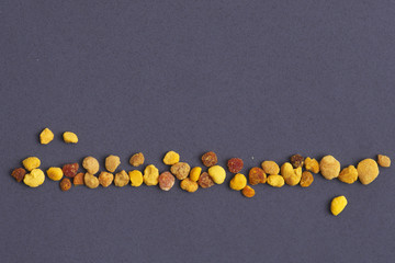 Macro photography of organic flower pollen superfood in line on purple background