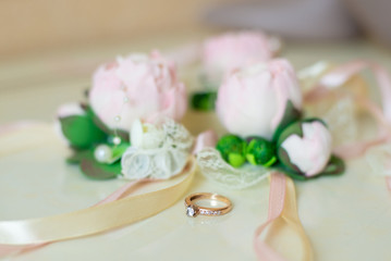 Engagement, wedding ring laying near roses boutonniere