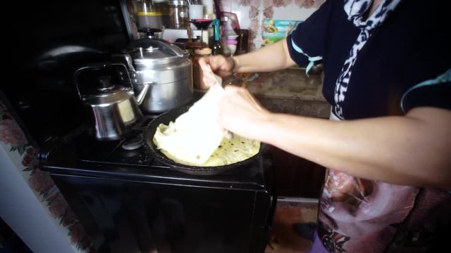 The most traditional Moroccan dishes. A Moroccan women cooking bread on a cast iron pan. making Rrissa.