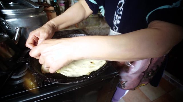 The most traditional Moroccan dishes. A Moroccan women cooking bread on a cast iron pan. making Rrissa.