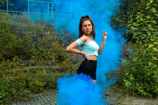 Young Girl Posing With Colored Smoke In An Abandoned Place