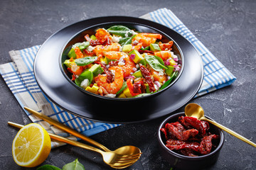shrimp avocado spinach salad in a black bowl