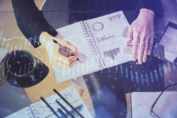 Multi exposure of hands making notes with forex chart huds. Stock market concept.