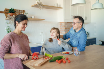 Mom, dad and daughter are cooking on kitchen. Happy family concept. Handsome man, attractive young woman and their cute little daughter are making food together. Healthy lifestyle.